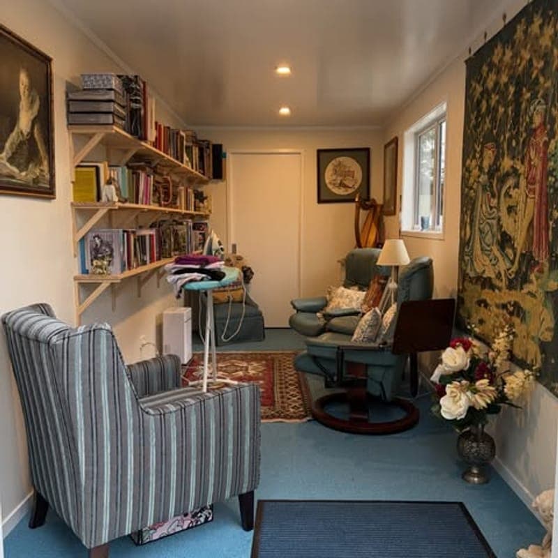 Finished garden studio interior with lined walls, recessed lighting, bookshelves and armchairs